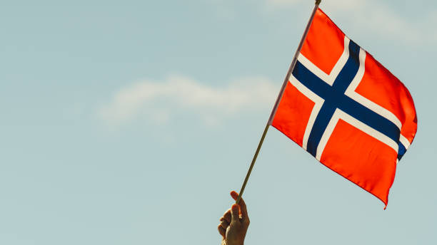 istock Hand holds norwegian flag against sky 1165368462