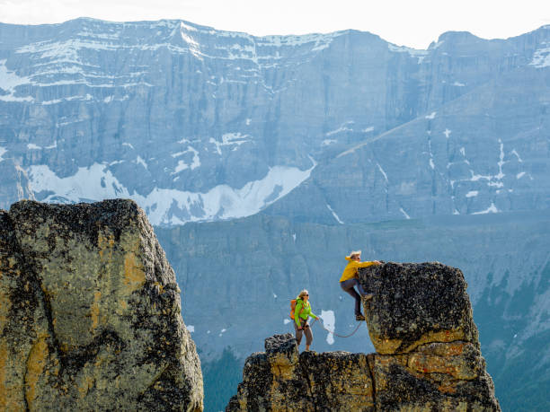 istock Mountaineers scale rocks steps on cliff with rope 1165368480