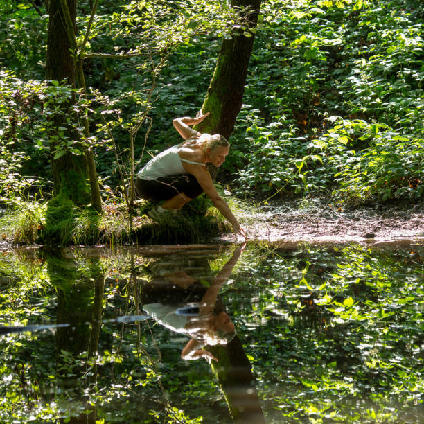 Mature woman relaxes in forest by pond