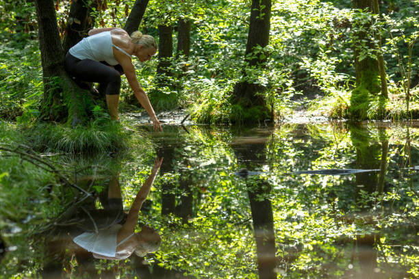 istock Mature woman relaxes in forest by pond 1165368545