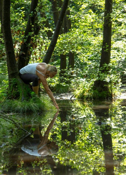 istock Mature woman relaxes in forest by pond 1165368669