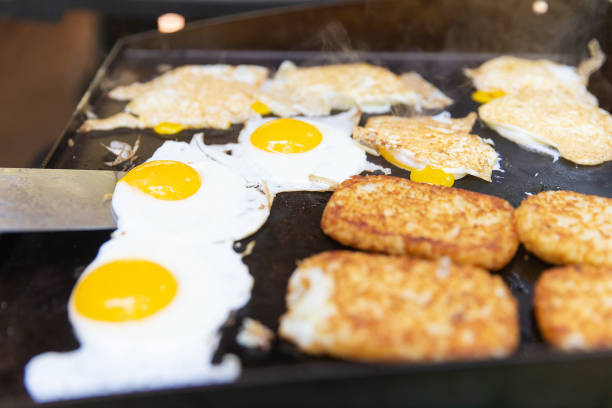 Hot breakfast cooking on outdoor flat grill while camping Hot breakfast cooked on a flat grill griddle stock pictures, royalty-free photos & images