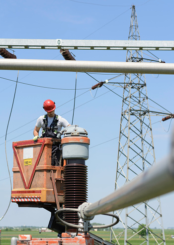 Manual worker fixing power lines in power substation. Working in high.