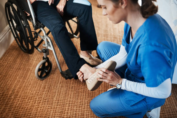 Starting her first day on the right foot Shot of a young nurse putting on a senior woman’s shoes in a nursing home getting dressed photos stock pictures, royalty-free photos & images