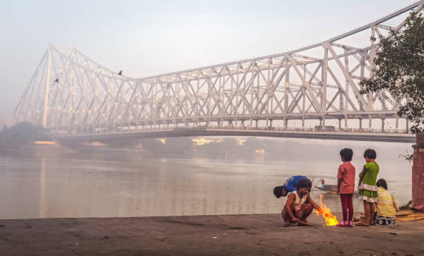 straßenbewohner halten sich warm, indem sie an einem wintermorgen in der nähe der historischen howrah-brücke in kalkutta, indien, brennen - street child stock-fotos und bilder