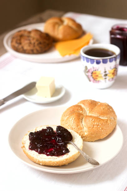 Breakfast with Kaiser rolls, currant jam, butter and cheese and tea. Selective focus.
