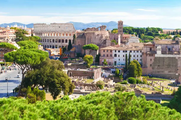 Ruins of Colosseo, Templum Pacis (Forum of Vespasian) and Tempio di Venere e Roma among many high green trees. Old town of Rome, Italy. Sunny autumn day. Shot from above