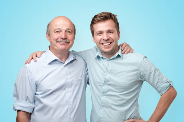 istock Old and young men standing together on blue studio wall. 1165376878