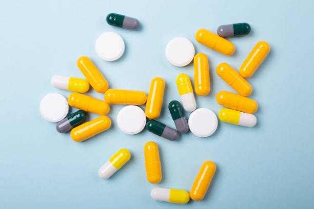 istock Multicolor tablets and pills capsules on blue background Close-up 1165377110