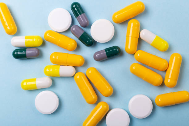 istock Multicolor tablets and pills capsules on blue background Close-up 1165377114