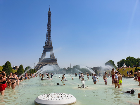 Paris, France, June 27, 2019: tourists and local taking a bath in the Jardins du Trocad ro Guardians of the Trocadero under the powerful water cannons