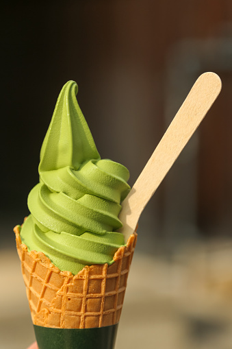 KYOTO, JAPAN - May 03, 2019: A cone of green tea Matcha soft ice cream with a wooden spoon