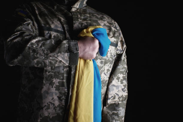 o soldado ucraniano prende em sua mão a bandeira amarelo-azul do estado, ele pressionou sua mão a sua caixa - pants green camouflage men - fotografias e filmes do acervo