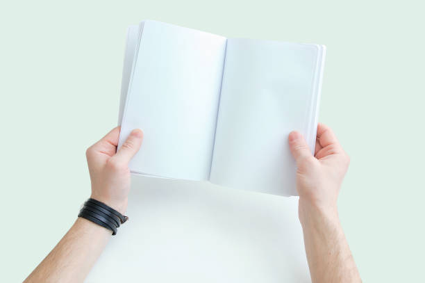 istock Caucasian man holding white open notebook in his hands. View from above. White background. 1165390421