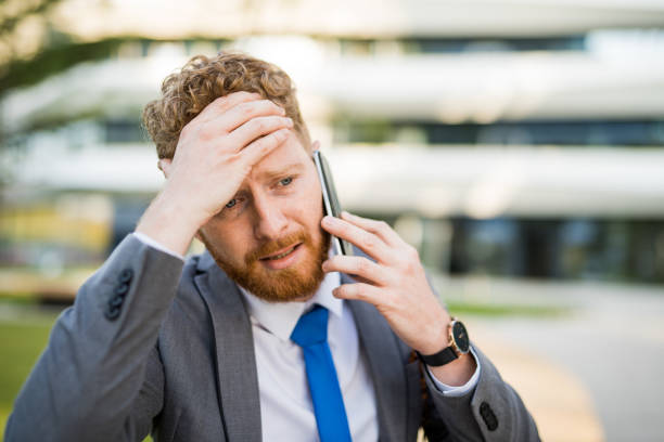 joven empresario en un teléfono que se encuentra con una crisis. - overworked worried distraught front view fotografías e imágenes de stock