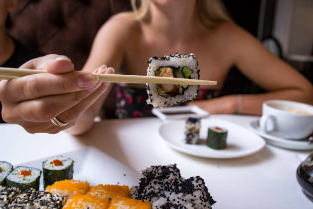 istock Woman is holding sushi roll in bamboo sticks. 1165392142