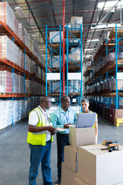 istock Warehouse staffs discussing over laptop in warehouse 1165393173