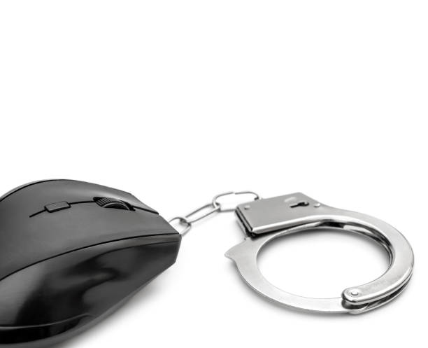 istock Computer addiction and cyber crime concept. Computer mouse with handcuffs on a white background. 1165396334