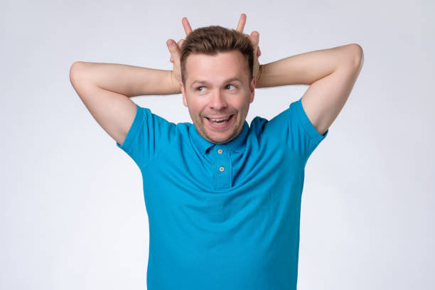 istock man standing with horns hand gesture on head and looking at camera 1165400022