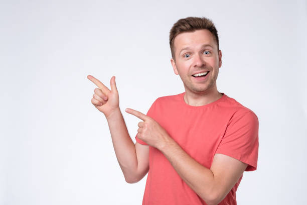 istock Happy man looking at camera, smiling and pointing aside with hand. 1165400762