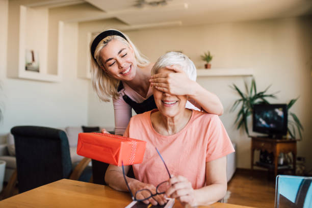 mädchen bedeckt mutter augen und geben ihr geschenk - people care surprise love stock-fotos und bilder