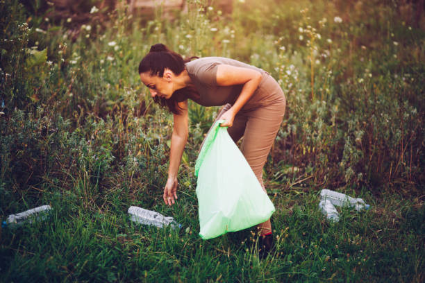 istock Female volunteer picks up trash in park 1165407648