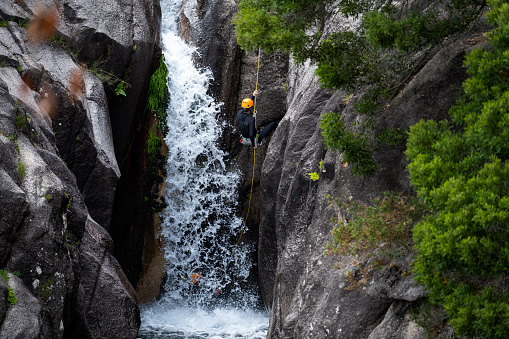 One man rappelling the Arado Waterfall (cascata do arado) in the Peneda Geres National Park, in Portugal.