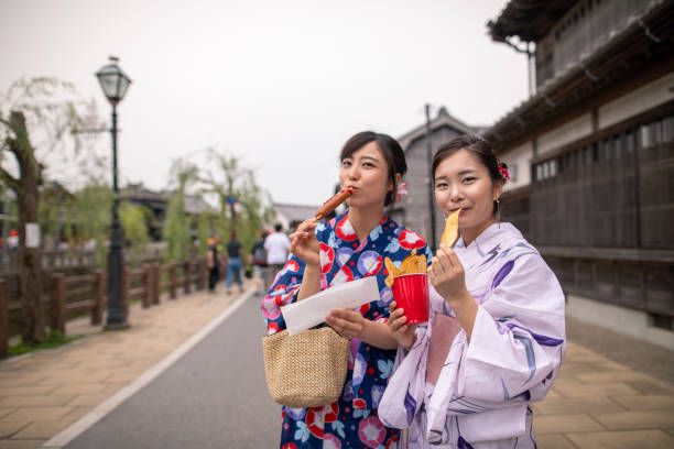 Young women in yukata eating foods on street Young women in yukata eating foods on street yukata photos stock pictures, royalty-free photos & images