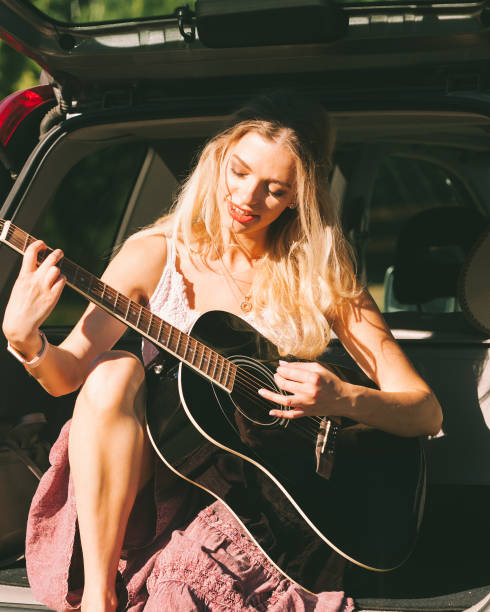 istock Girl with guitar on hatchback car 1165417140