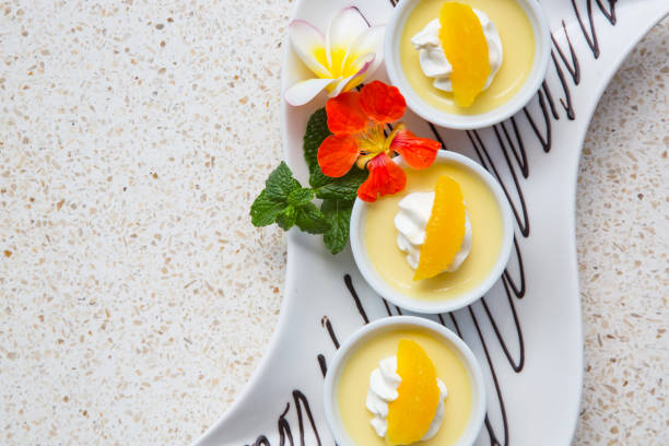 istock Vanilla pudding with whipped cream and a slice of orange elegantly served on a long tray 1165417852