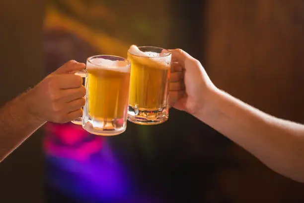 Two people toasting with mugs full beer