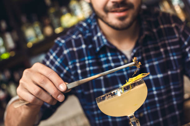 istock Young bartender standing at bar counter decorating cocktail with herb smiling close-up 1165422577