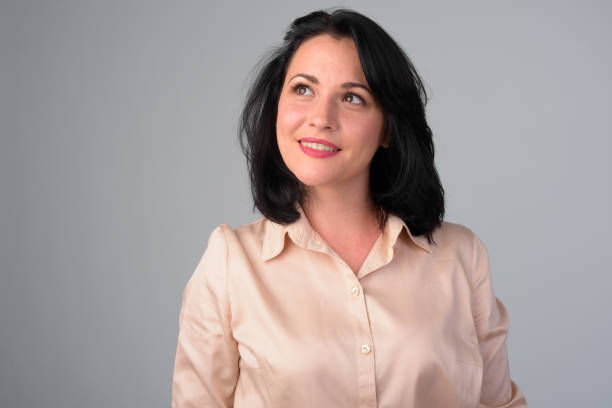 istock Happy beautiful businesswoman thinking while looking up against white background 1165424419