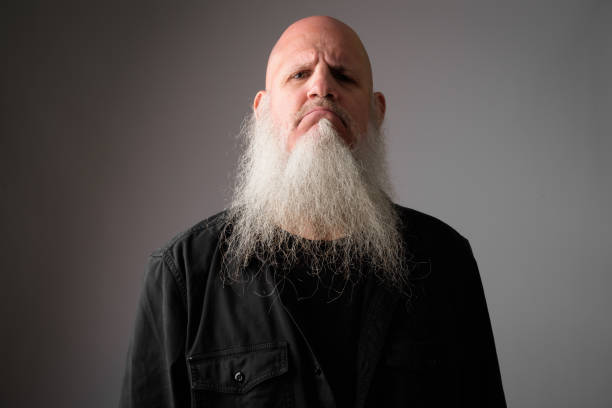 Face of mature bald bearded man looking angry Studio shot of mature bald man with long gray beard against white background. bald guys with beards stock pictures, royalty-free photos & images