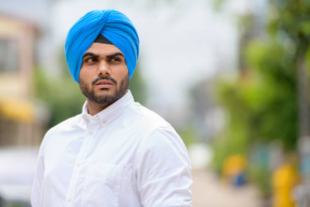 Portrait of young handsome bearded Indian Sikh man in the streets outdoors