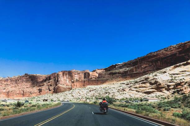 istock motorcycle driving on the road by red cliffs 1165428348