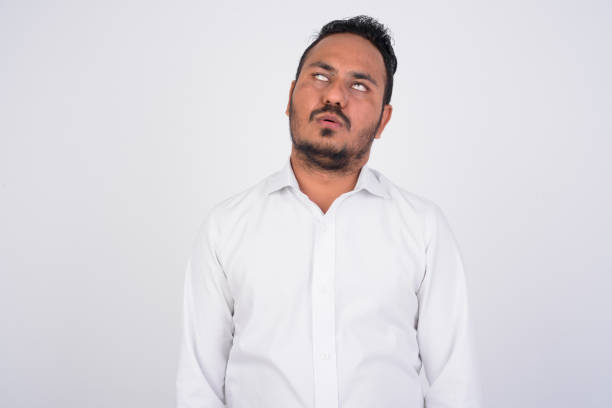 Studio shot of stressed bearded Indian businessman looking bored and tired Studio shot of bearded Indian businessman against white background rolling eyes irritation displeased facial expression stock pictures, royalty-free photos & images