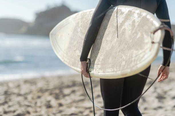 istock A female surfer walking along the beach 1165432099