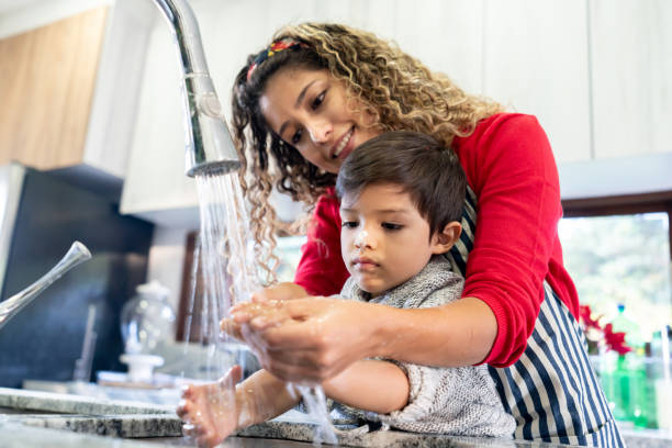 mutter hilft sohn waschen seine hand nach der herstellung von keksen - baking lifestyles beautiful cookie stock-fotos und bilder