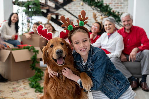 Beautiful portrait of a happy girl and her dog celebrating Christmas with the family and wearing reindeer ears