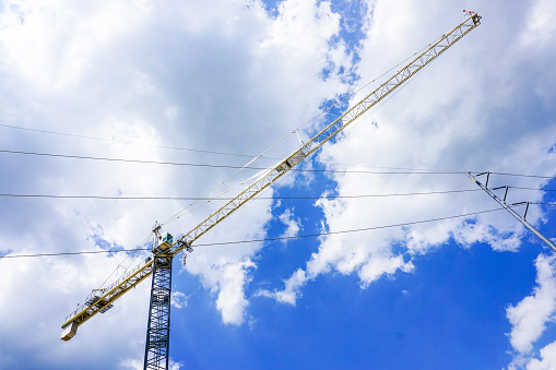 Tall construction crane and power lines against a bright blue sky