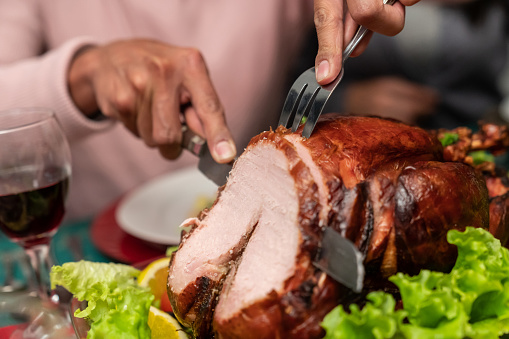 Close-up on a man cutting the turkey for the Christmas Eve dinner - holidays concepts