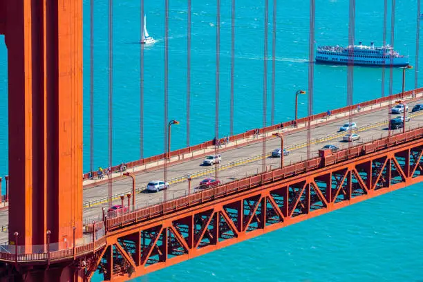 Close up aerial/ drone view on the famous iconic Golden Gate Bridge tourist attraction landmark structure in San Francisco, California on a sunny summer day. Vehicles driving on major road highway.