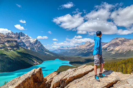 A young hiker looks at Peyto Lake from Bow Summit in Banff National Park on the Icefields Parkway. The glacier-fed lake is famous for its bright turquoise colored waters in the summer.