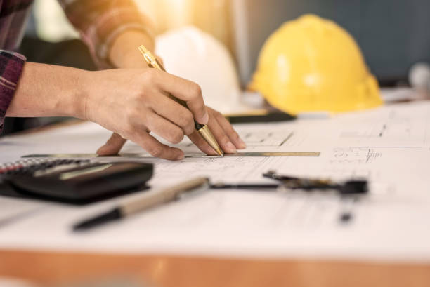 istock Female architect drawing blueprints in office workplace. 1165441568
