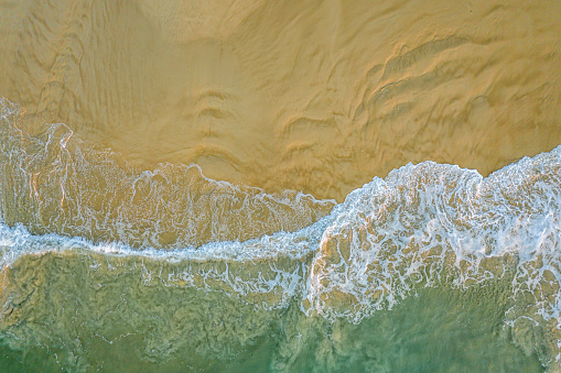An aerial view of a wave breaking onto a sandy beach in the National Park