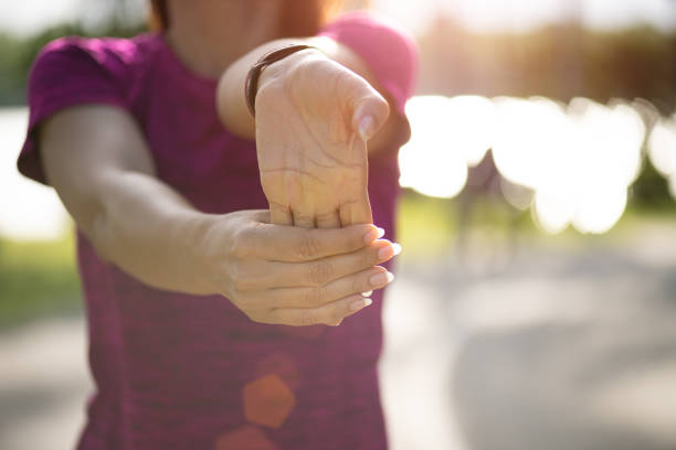 giovane fitness donna runner allungando la mano prima di correre nel parco. concetto di attività di esercizio all'aperto. - wrist foto e immagini stock