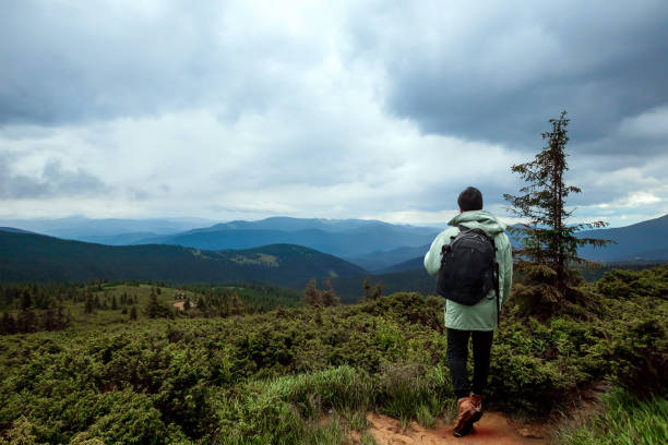 istock Creative background, A male tourist walks through a mountainous area with a backpack. The concept of active tourism, recreation, the Carpathians. Copy space 1165444304