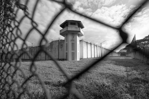 torre di guardia del carcere protetta da filo di recinzione carceraria. muro di prigione bianco e torre di guardia con filo spinato arrotolato. concetto di detenzione di giustizia penale - vigilanza tower foto e immagini stock