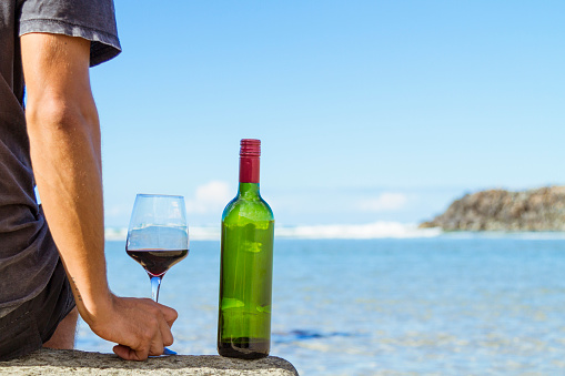 Young man enjoying wine at the beach on a sunny day drinking Australian Wine.